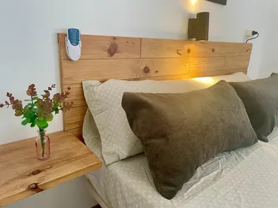 a bed with a wooden headboard with a vase of flowers on it at GATU Casa Muse junto a la playa, vista al mar, aire acc, terraza, wifi y chimenea 