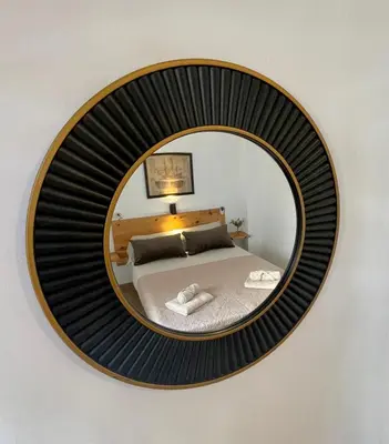 a round mirror with a bed in a bedroom at GATU Casa Muse junto a la playa, vista al mar, aire acc, terraza, wifi y chimenea 