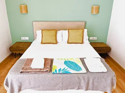 a bedroom with a bed with white sheets and yellow pillows at Villa Velero - Ole Solutions in Sanlúcar de Barrameda