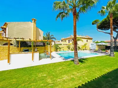 a villa with a swimming pool and palm trees at Villa Velero - Ole Solutions in Sanlúcar de Barrameda