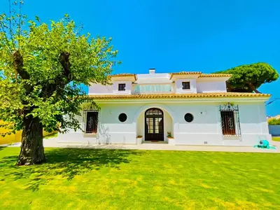 a large white house with a tree in the yard at Villa Velero - Ole Solutions in Sanlúcar de Barrameda