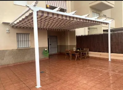 a pergola with a table and chairs in a patio at Puerta de Doñana: Playa y centro a un paso. in Sanlúcar de Barrameda