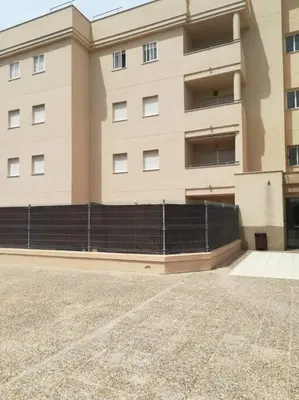 a large building with a fence in front of it at Puerta de Doñana: Playa y centro a un paso. in Sanlúcar de Barrameda