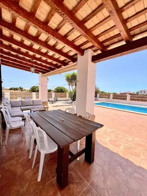 a wooden table and chairs on a patio with a pool at Casa Con Encanto 2 SOLO FAMILIAS in Conil de la Frontera