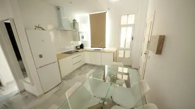 a white kitchen with a glass table and white chairs at Allo Apartments Larga Hideaway Parking Centro 2 Habitaciones in Jerez de la Frontera