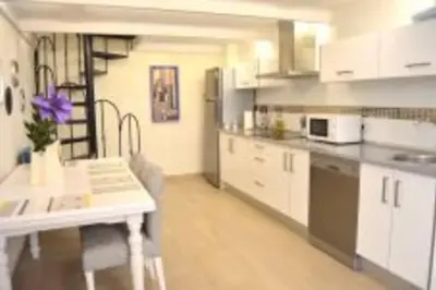 a kitchen with white cabinets and a white table and a counter at APARTAMENTO VEEDOR BULEVAR DE LOS SUEÑOS in Cádiz