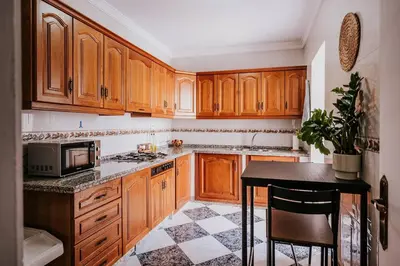 a kitchen with wooden cabinets and a table with a microwave at Apartamento Valdés - Ole Solutions in El Puerto de Santa María
