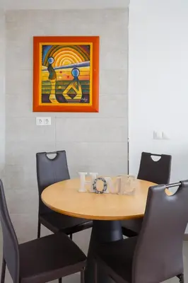 a table with chairs and a painting on the wall at POSEIDON Beach Apartment & parking by Cadiz4Rentals in Cádiz