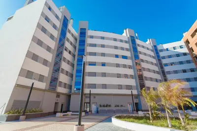 a large white building with trees in front of it at POSEIDON Beach Apartment & parking by Cadiz4Rentals in Cádiz