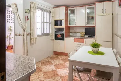 a kitchen with white cabinets and a table and chairs at Casa RECREO in Cádiz
