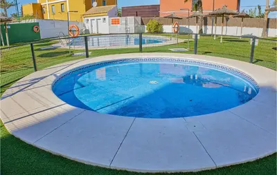 an empty swimming pool with blue water in a yard at Cozy Apartment In Sanlúcar De Barrameda in Sanlúcar de Barrameda