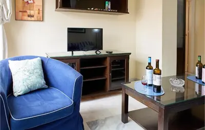 a living room with a blue chair and a table with wine bottles at Cozy Apartment In Sanlúcar De Barrameda in Sanlúcar de Barrameda