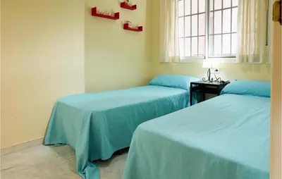two beds in a room with blue sheets and a window at Cozy Apartment In Sanlúcar De Barrameda in Sanlúcar de Barrameda