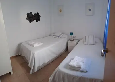 two beds in a room with white walls at Geranio Chipionahome in Chipiona