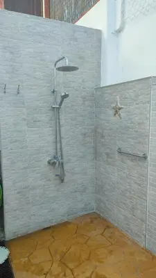 a shower in a bathroom with a stone wall at Geranio Chipionahome in Chipiona