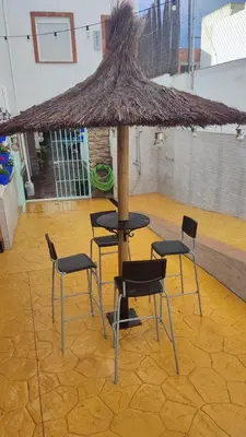 a table and chairs under a straw umbrella at Geranio Chipionahome in Chipiona