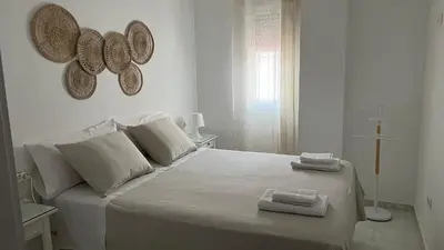 a white bedroom with a large bed with two towels on it at Casa vacacional equipada in Lebrija