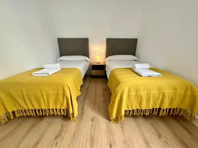 two beds in a room with yellow blankets at Apartamentos La Muralla Grupo AC Gestion in Cádiz