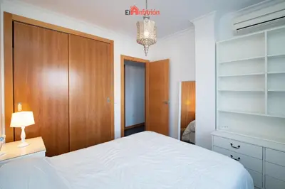 a bedroom with a white bed and a wooden closet at El Anfitrión - Paleobull Castillo in Sanlúcar de Barrameda