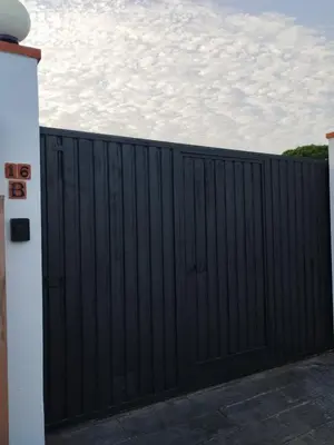 a black gate in a driveway with a cloudy sky in the background at Casita Alejandro in Chiclana de la Frontera