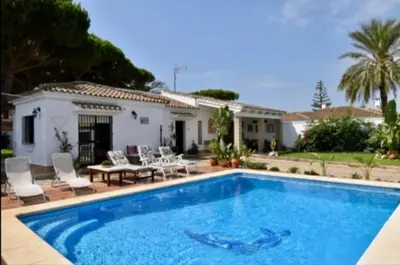 a swimming pool in front of a house at Villa Mencal in Chiclana de la Frontera