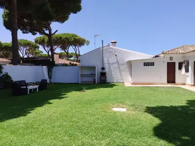 a yard with a white house and a white fence at Villa Mencal in Chiclana de la Frontera
