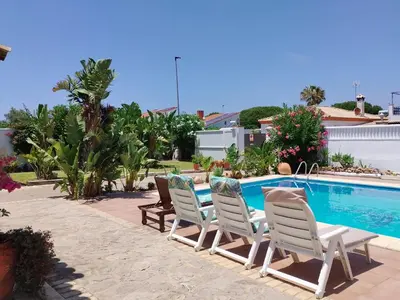a group of chairs sitting next to a swimming pool at Villa Mencal in Chiclana de la Frontera