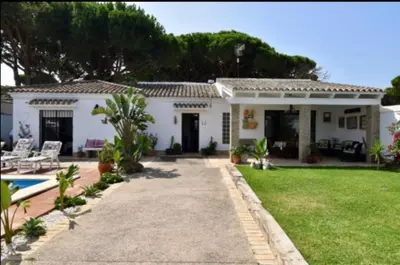 a white house with a yard and a pool at Villa Mencal in Chiclana de la Frontera