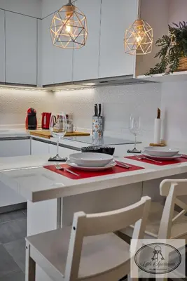 a kitchen with white cabinets and a table with wine glasses at Apartamento Playa Recreo Little Apartments in Cádiz