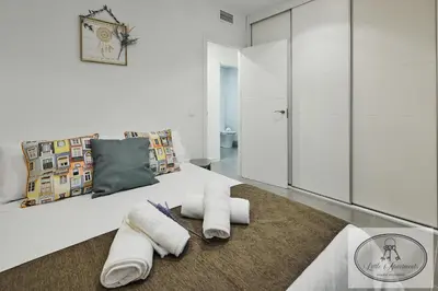 a bedroom with a white bed with towels on the floor at Apartamento Playa Recreo Little Apartments in Cádiz