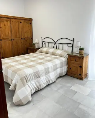 a bedroom with a bed and a wooden cabinet at A menos d 1 min d plaza cabildo in Sanlúcar de Barrameda