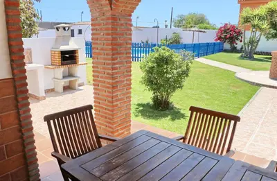 a table and chairs on a patio with a grill at Chalet Florida III in Conil de la Frontera