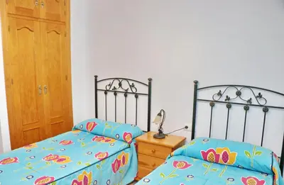 a bedroom with two beds and a wooden door at Chalet Florida III in Conil de la Frontera