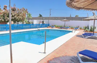 a swimming pool with chairs and umbrellas at Chalet Florida III in Conil de la Frontera