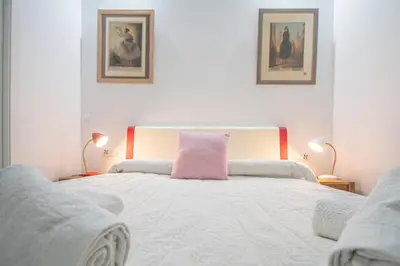a bedroom with a bed with a pink pillow on it at Apartamento El Cobijo de Cádiz in Cádiz