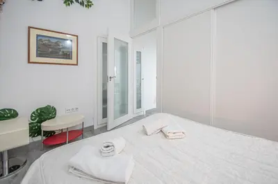 a white room with a bed and a chair at Apartamento El Cobijo de Cádiz in Cádiz