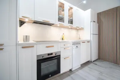 a white kitchen with white cabinets and a refrigerator at Apartamento El Cobijo de Cádiz in Cádiz