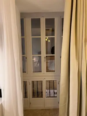 a white cabinet with glass doors in a room with curtains at Apartamento El Alquimista in Cádiz