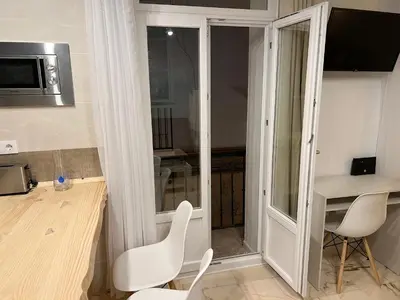 a small kitchen with white chairs and a table at Apartamento El Alquimista in Cádiz
