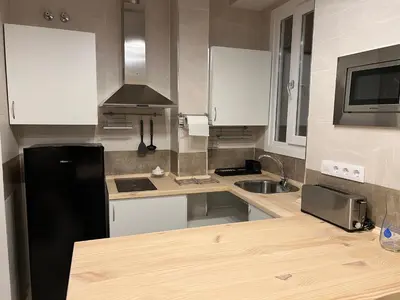 a kitchen with white cabinets and a black refrigerator at Apartamento El Alquimista in Cádiz