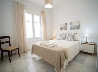 a white bedroom with a bed with towels on it at Sibs Sanlucar-San Juan-Cabildo Centro Playa Familias Amigos in Sanlúcar de Barrameda