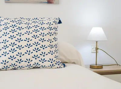 a bed with a blue and white pillow and a lamp at Sibs Sanlucar-San Juan-Cabildo Centro Playa Familias Amigos in Sanlúcar de Barrameda