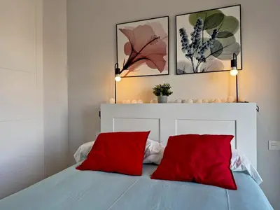 a bedroom with a bed with two red pillows at Apartamento Alazán - Ole Solutions in Jerez de la Frontera