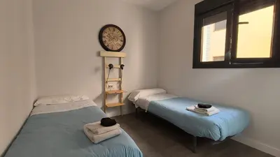 two beds in a room with a clock on the wall at Kiana Mirador Sherry, parking gratis in Jerez de la Frontera
