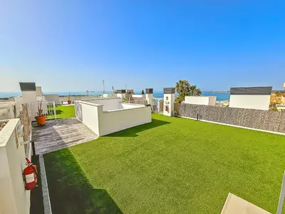 a large backyard with a yard with green grass at Oceanfront Duplex with a Rooftop Pool and Terrace in El Puerto de Santa María