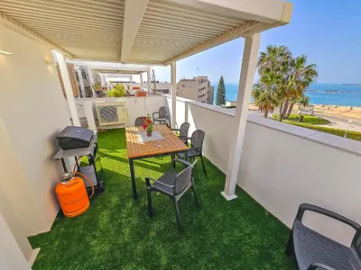 a balcony with a table and chairs and the ocean at Oceanfront Duplex with a Rooftop Pool and Terrace in El Puerto de Santa María