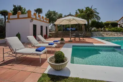 a swimming pool with lounge chairs and an umbrella at Finca La Fuensanta in Arcos de la Frontera