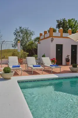 a swimming pool with two lounge chairs and a house at Finca La Fuensanta in Arcos de la Frontera