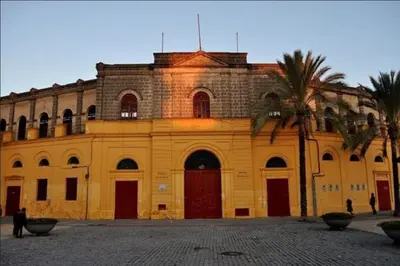 a yellow building with palm trees in front of it at Apartamento Juan Belmonte in Jerez de la Frontera