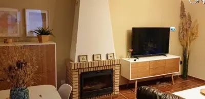 a living room with a fireplace and a flat screen tv at Orchard View in Campano